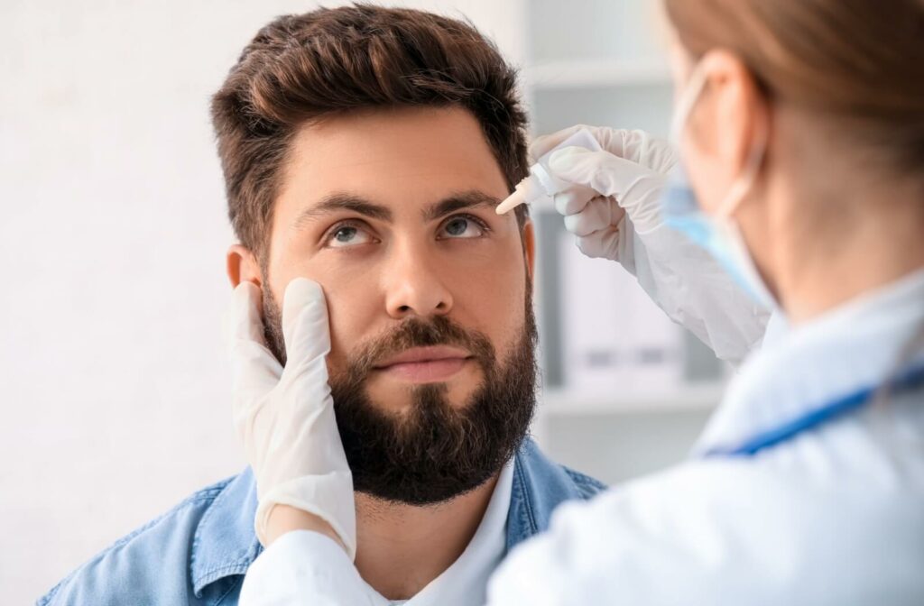 A healthcare professional applying eye drops to a patient's eye during a check-up.